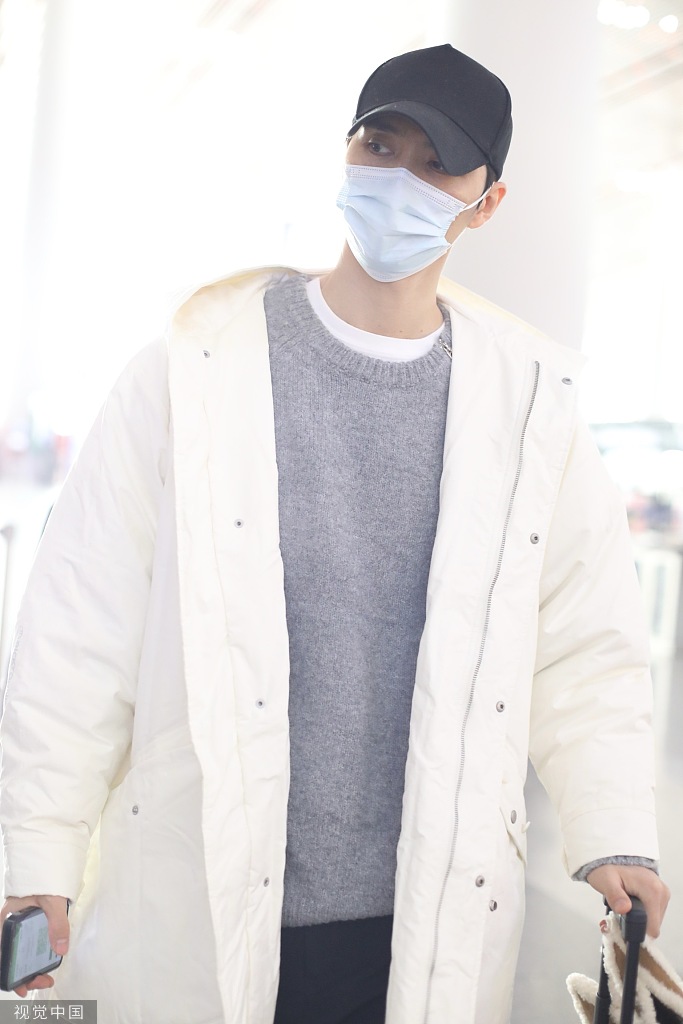 阿云嘎穿白色羽绒服现身机场 遇粉丝送信警戒放包中
